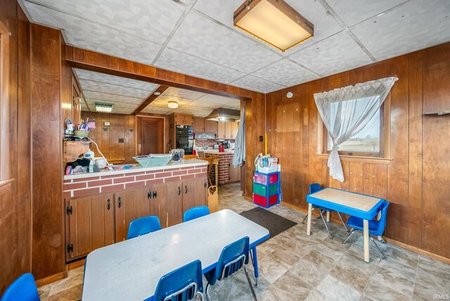 dining room with wooden walls and a drop ceiling