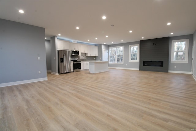 unfurnished living room with a fireplace, light hardwood / wood-style flooring, and a wealth of natural light