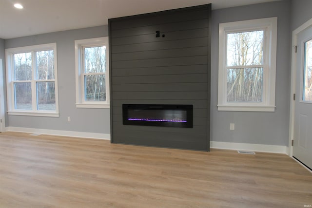 unfurnished living room featuring a healthy amount of sunlight, light hardwood / wood-style floors, and a fireplace