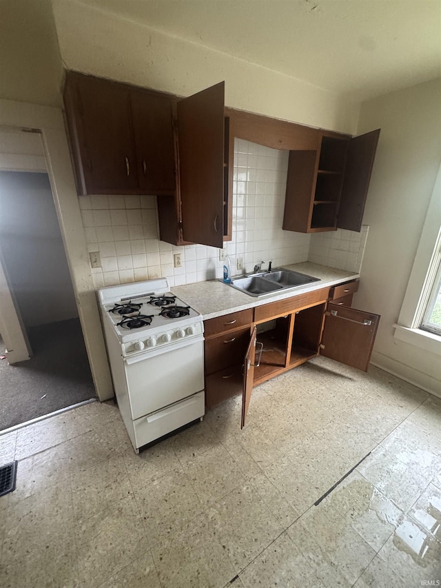 kitchen featuring white range with gas cooktop, open shelves, a sink, tasteful backsplash, and dark brown cabinets