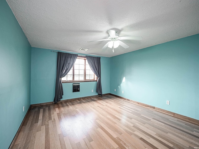 unfurnished room with ceiling fan, a textured ceiling, and light wood-type flooring