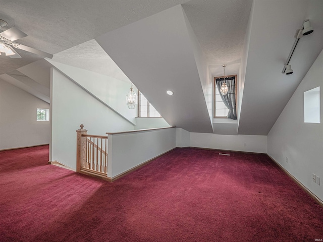 additional living space featuring a textured ceiling, ceiling fan with notable chandelier, carpet floors, and vaulted ceiling