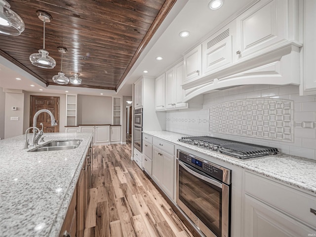 kitchen with white cabinets, pendant lighting, sink, and a tray ceiling