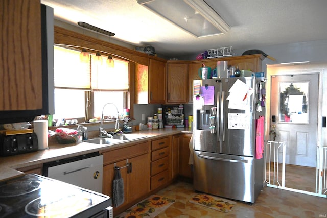 kitchen featuring stainless steel fridge, sink, dishwasher, and a textured ceiling