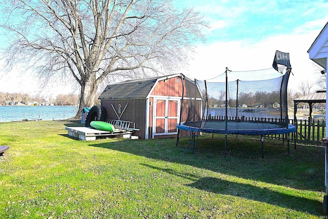 view of yard featuring a trampoline, a water view, and a storage unit