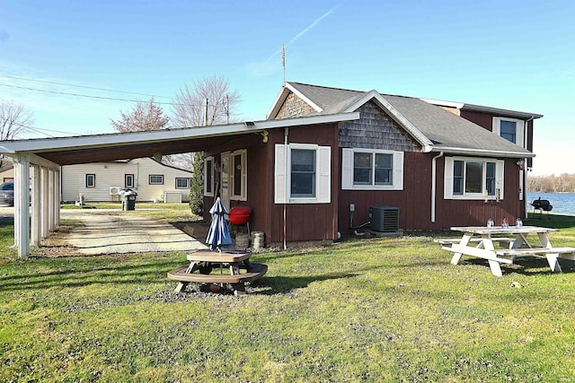 rear view of property featuring a yard, central AC, and a carport