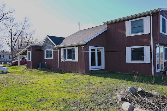 back of house with central air condition unit and a yard