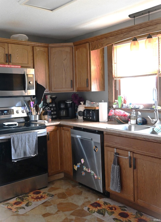 kitchen featuring appliances with stainless steel finishes, a textured ceiling, hanging light fixtures, and sink