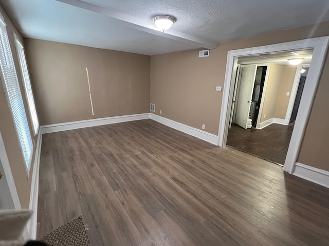 empty room with dark hardwood / wood-style flooring and a textured ceiling