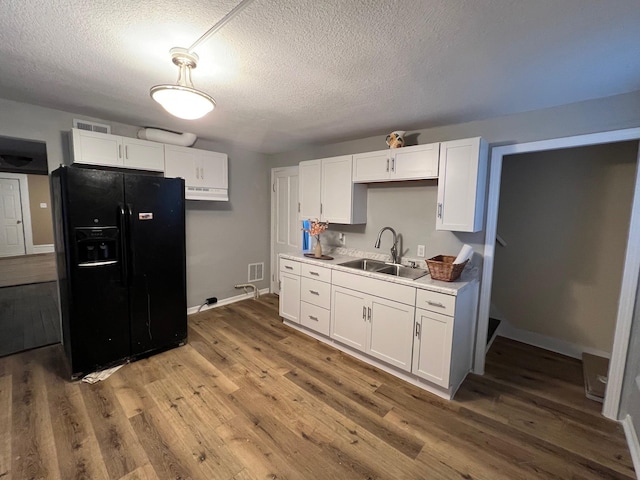 kitchen featuring sink, black refrigerator with ice dispenser, a textured ceiling, white cabinets, and hardwood / wood-style flooring