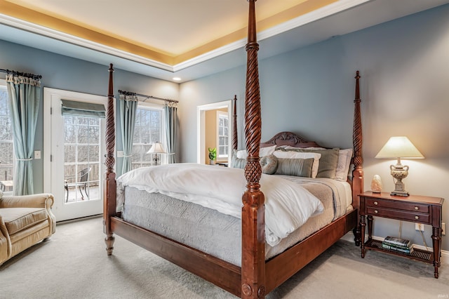 carpeted bedroom with a raised ceiling and access to outside