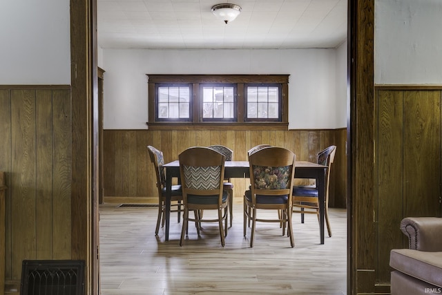 dining room featuring light hardwood / wood-style floors and wooden walls