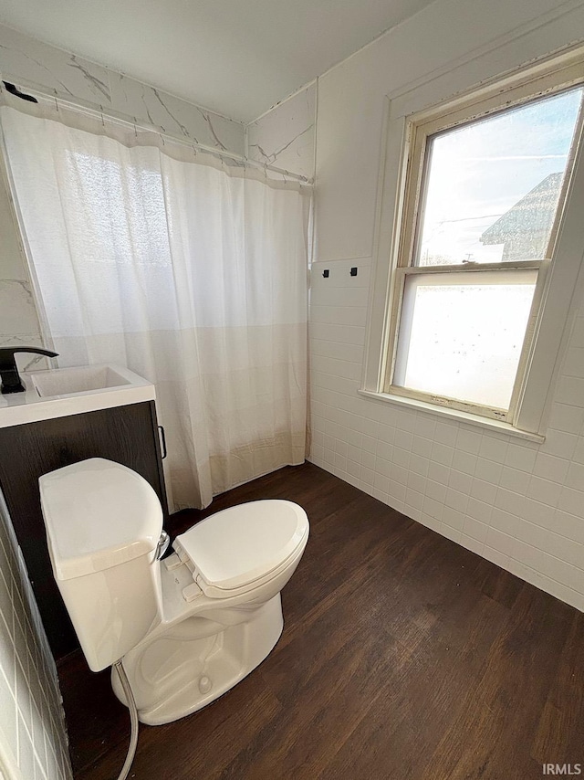 bathroom with hardwood / wood-style flooring, vanity, tile walls, and toilet