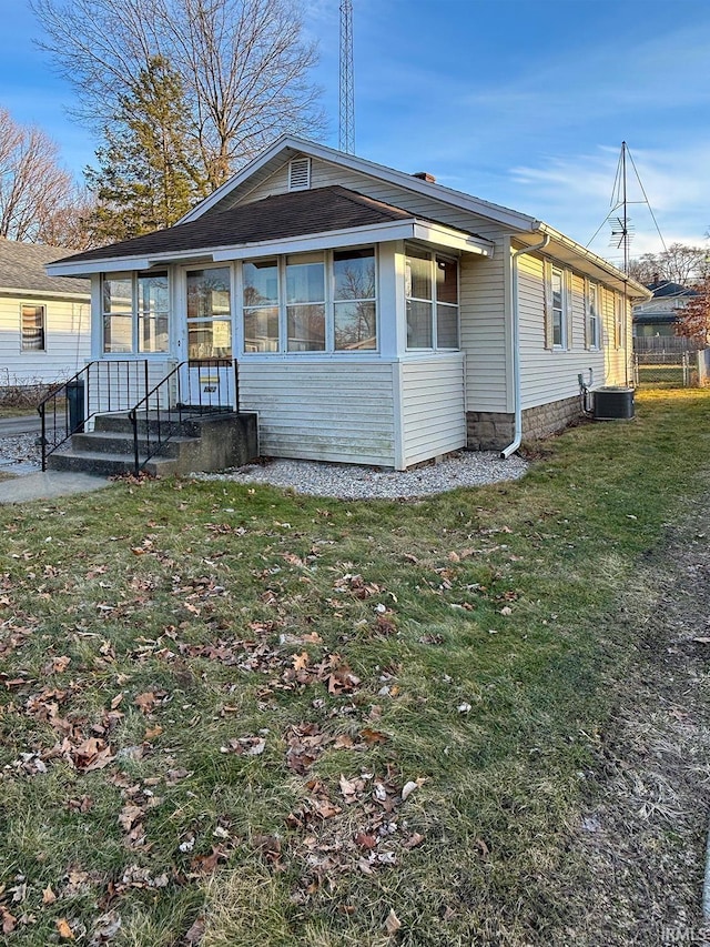 back of property featuring central AC and a lawn