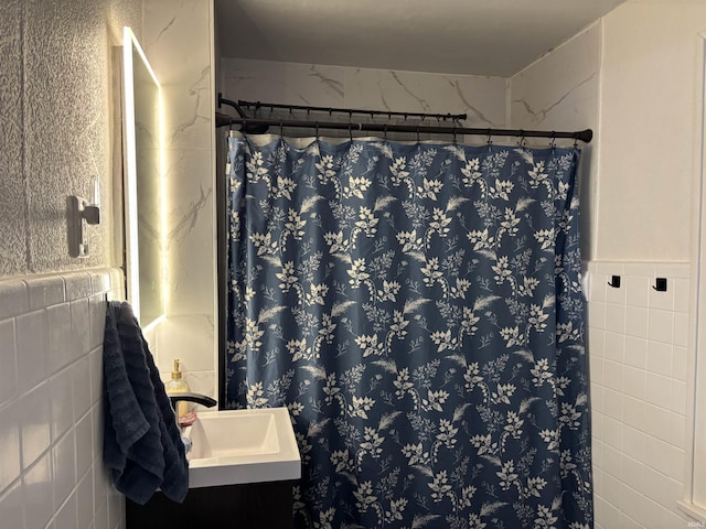 bathroom with a shower with shower curtain, sink, and tile walls