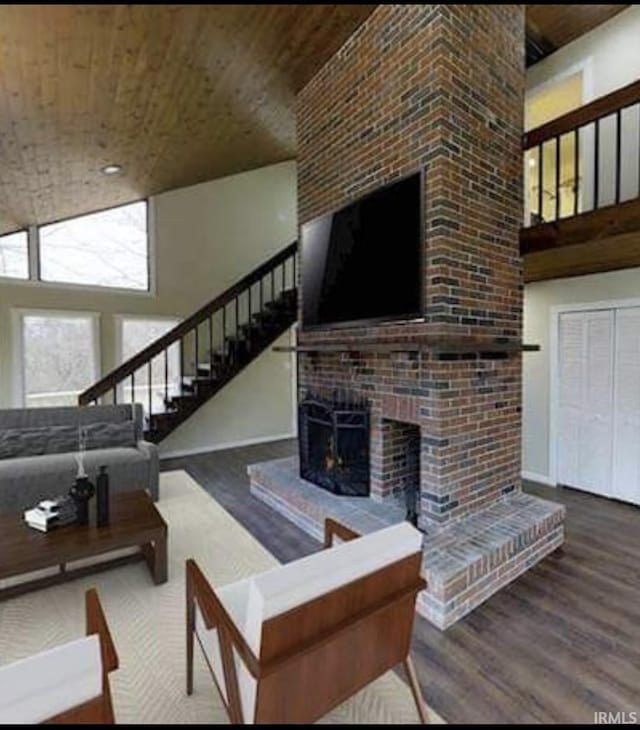 living room featuring a towering ceiling, hardwood / wood-style flooring, a brick fireplace, and wood ceiling