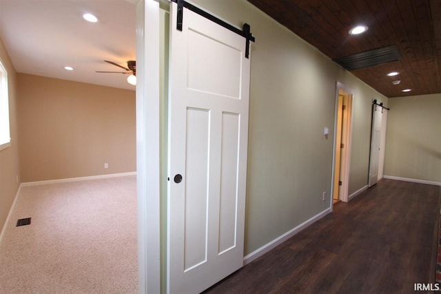 corridor featuring a barn door, dark wood-type flooring, and wood ceiling