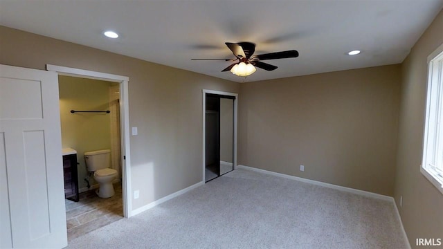 unfurnished bedroom with ceiling fan, a closet, ensuite bathroom, and light carpet