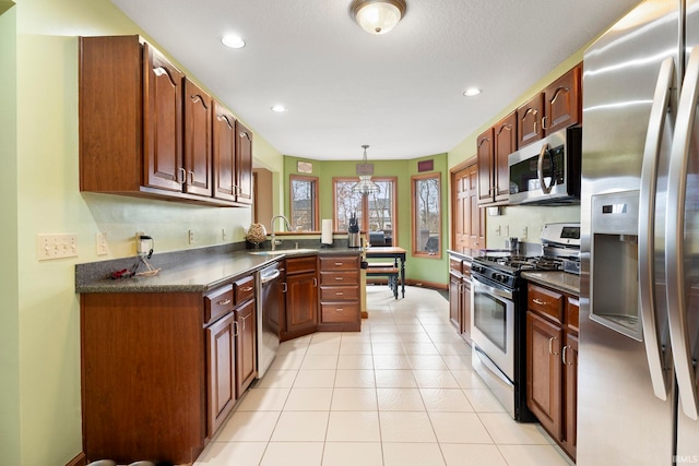 kitchen with appliances with stainless steel finishes, light tile patterned floors, pendant lighting, and sink