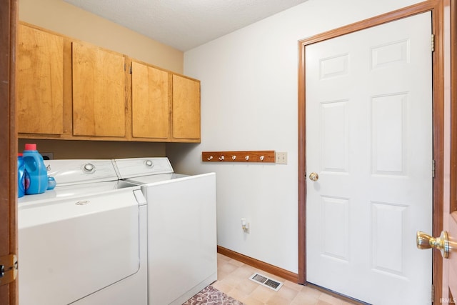 laundry area featuring washer and dryer, cabinets, and a textured ceiling