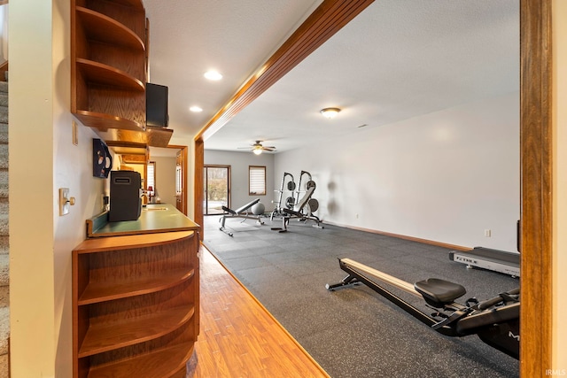 workout room featuring hardwood / wood-style floors, ceiling fan, and a textured ceiling