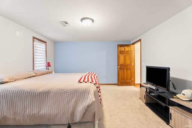 bedroom featuring light colored carpet and a textured ceiling