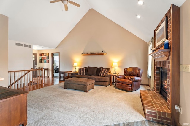 living room featuring wood-type flooring, high vaulted ceiling, a brick fireplace, and ceiling fan