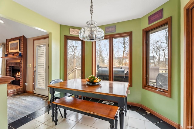 dining area featuring a chandelier, wood-type flooring, and a brick fireplace