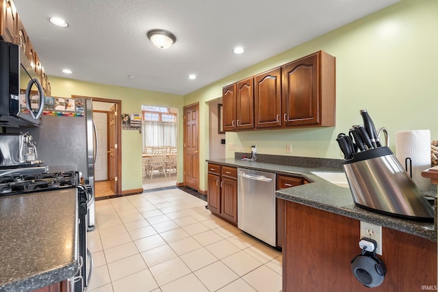 kitchen featuring light tile patterned floors, a textured ceiling, and stainless steel appliances