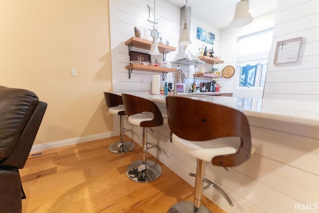 bar with pendant lighting and light hardwood / wood-style floors