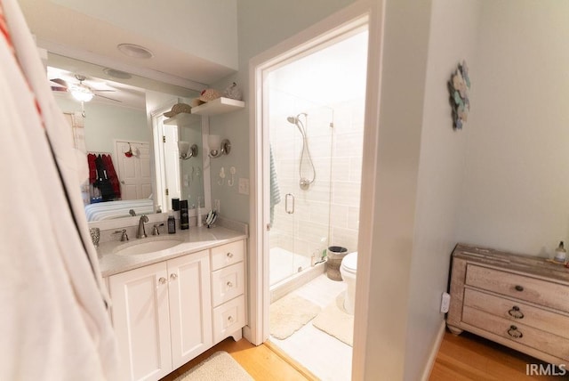 bathroom with ceiling fan, walk in shower, hardwood / wood-style floors, toilet, and vanity