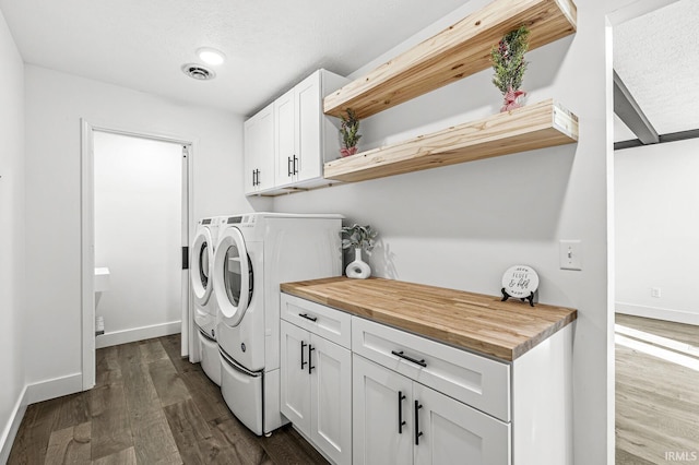 washroom with cabinets, a textured ceiling, dark hardwood / wood-style floors, and washer and clothes dryer