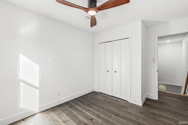 unfurnished bedroom with ceiling fan, dark wood-type flooring, and a closet