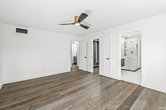 unfurnished bedroom with connected bathroom, ceiling fan, and dark wood-type flooring