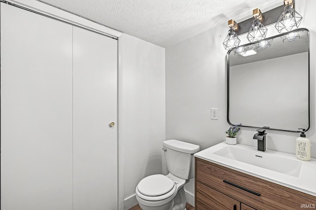 bathroom featuring vanity, a textured ceiling, and toilet