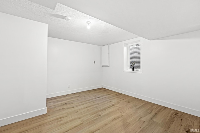 spare room with a textured ceiling and light wood-type flooring