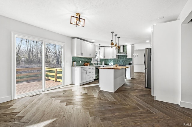 kitchen with wood counters, a center island, hanging light fixtures, appliances with stainless steel finishes, and white cabinetry