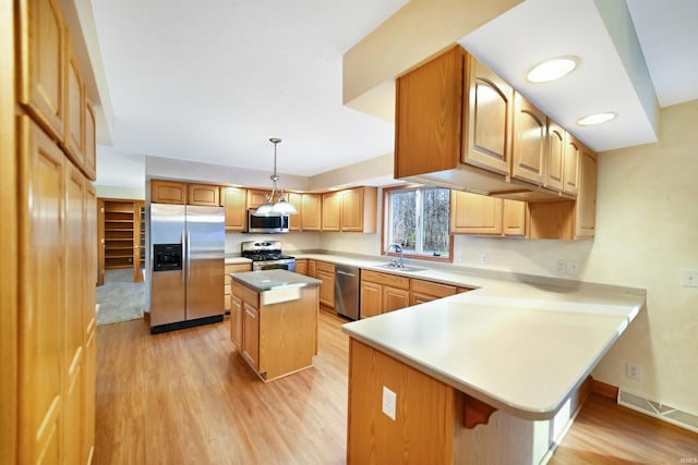 kitchen featuring a center island, light hardwood / wood-style flooring, kitchen peninsula, pendant lighting, and appliances with stainless steel finishes