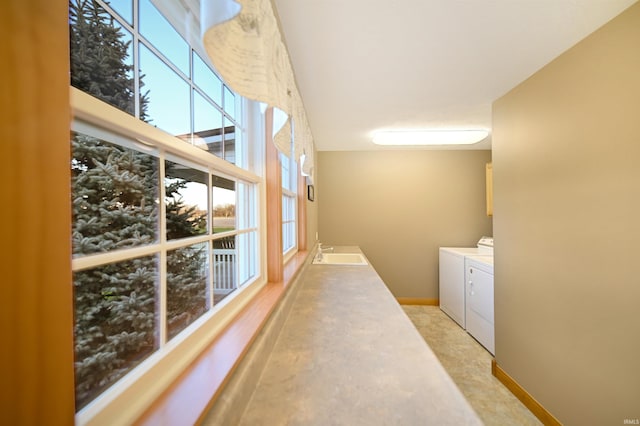 hall with washer and clothes dryer, light carpet, sink, and plenty of natural light