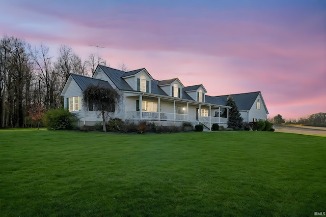 new england style home featuring a porch and a yard