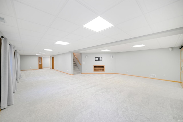 basement featuring a paneled ceiling and light colored carpet