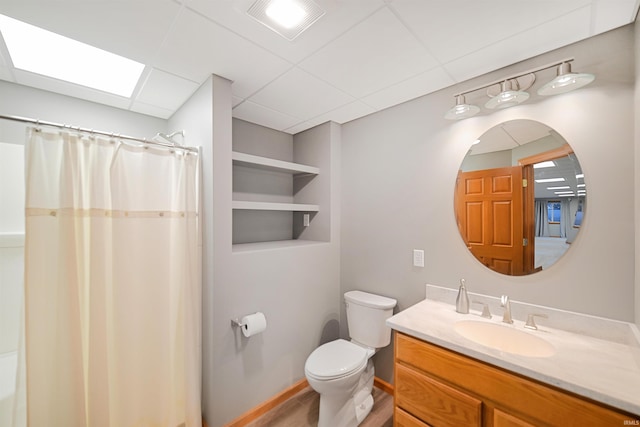 bathroom with a paneled ceiling, vanity, a skylight, and toilet