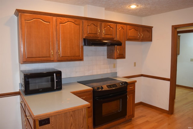 kitchen with backsplash, black appliances, a textured ceiling, and light wood-type flooring