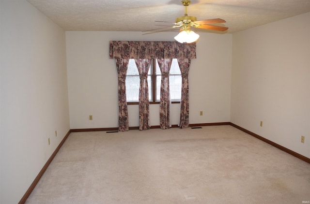 spare room featuring a textured ceiling, light colored carpet, and ceiling fan