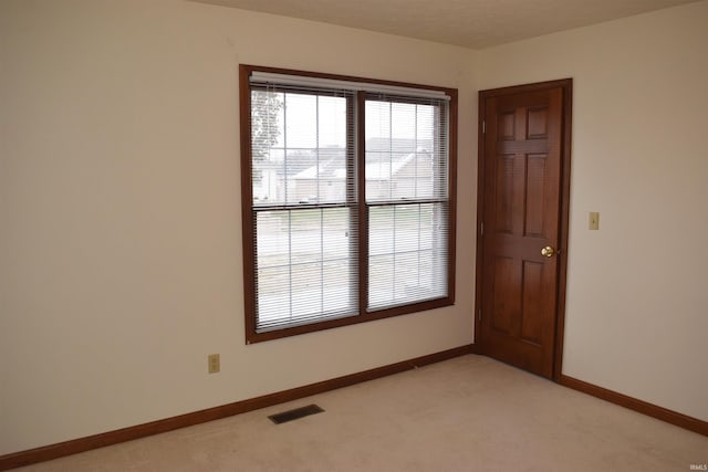 unfurnished room featuring a textured ceiling and light carpet