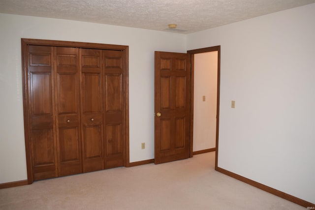 unfurnished bedroom with a textured ceiling, light colored carpet, and a closet