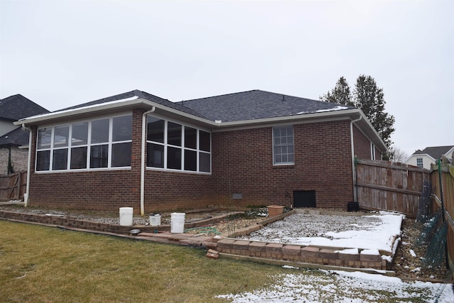 snow covered property featuring a sunroom and a yard