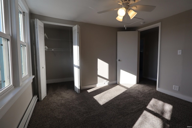 unfurnished bedroom featuring ceiling fan, a baseboard heating unit, dark carpet, and a closet