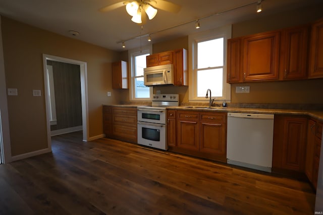 kitchen featuring white appliances, sink, rail lighting, ceiling fan, and dark hardwood / wood-style flooring