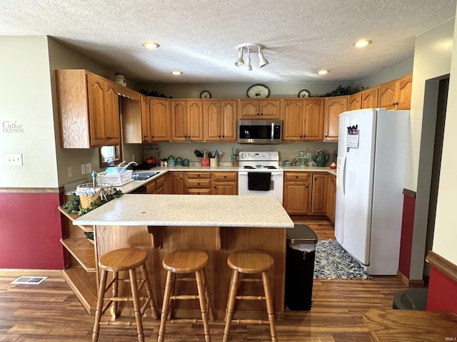 3020 10 Oclock Rd, Bloomingdale, IN 47832 - kitchen featuring white appliances, a peninsula, light countertops, wood finished floors, and a kitchen bar
